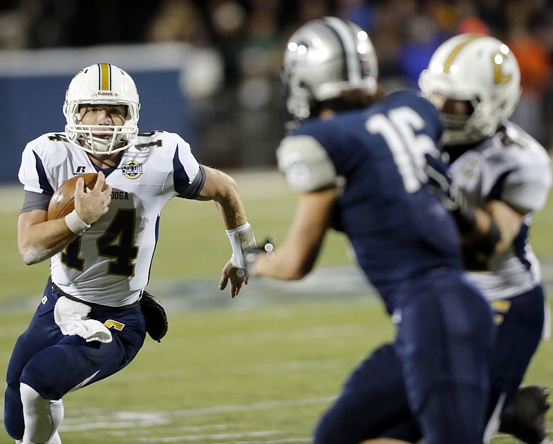 Chattanooga's Jacob Huesman (14) finds an opening past New Hampshire's Nick Cefalo to score in the first quarter during the NCAA FCS college football quarterfinals Friday, Dec. 12, 2014, in Durham,N.H. (AP Photo/Jim Cole)