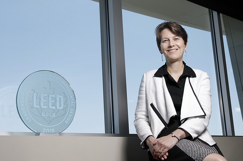 Dana Perry poses for a photo with a LEED Gold certification emblem at Chambliss, Bahner, & Stophel, P.C., on Thursday, Aug. 13, 2015, in Chattanooga, Tenn. The law firm is LEED Gold certified.