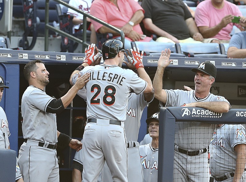 Miami Marlins center fielder Cole Gillespie (28) is greeted at the dugout entrance by Miami Marlins third baseman Martin Prado, left, and manager Dan Jennings after hitting a solo home run in the second inning of a baseball game against the Atlanta Braves on Monday, Aug. 31, 2015, in Atlanta. 