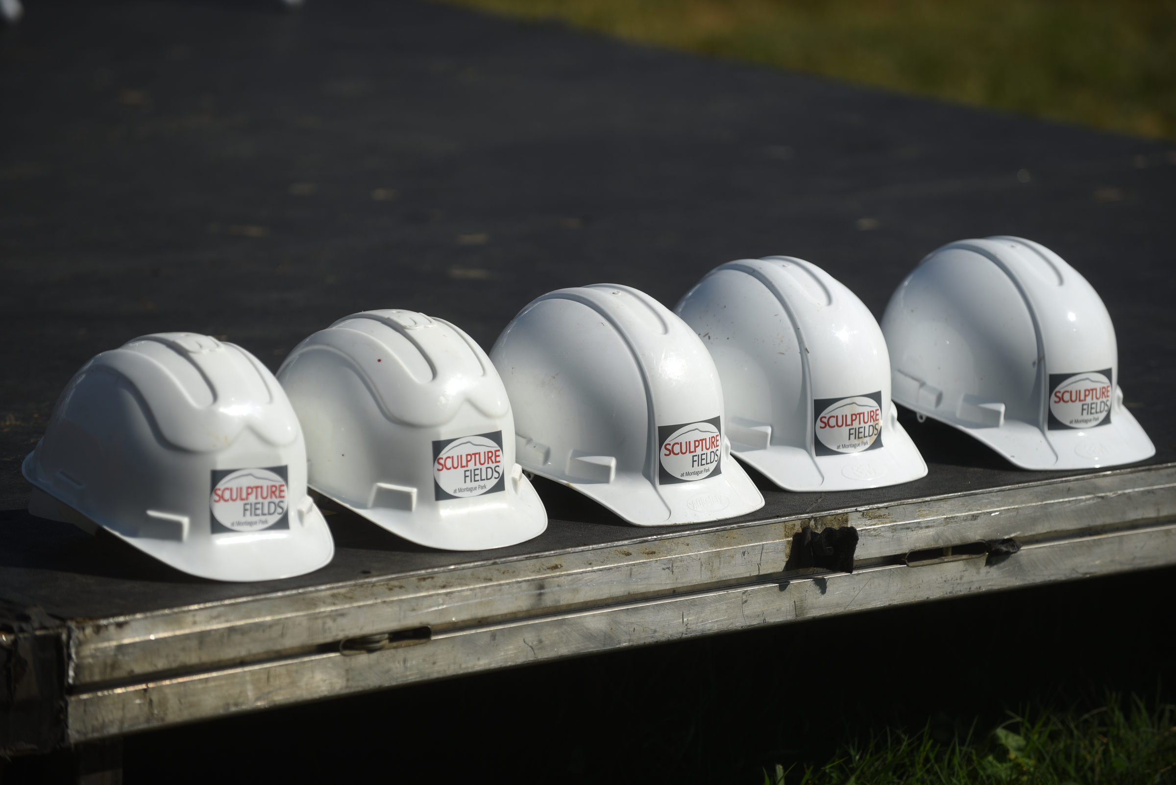 Five hard hats sit in a line as a crane raises a 65-foot-tall sculpture Tuesday, September 1, 2015, at the Sculpture Fields at Montague Park as a tribute to honor the five military members who were slain in July. Artist Peter Lundberg created the sculpture, named Anchors.