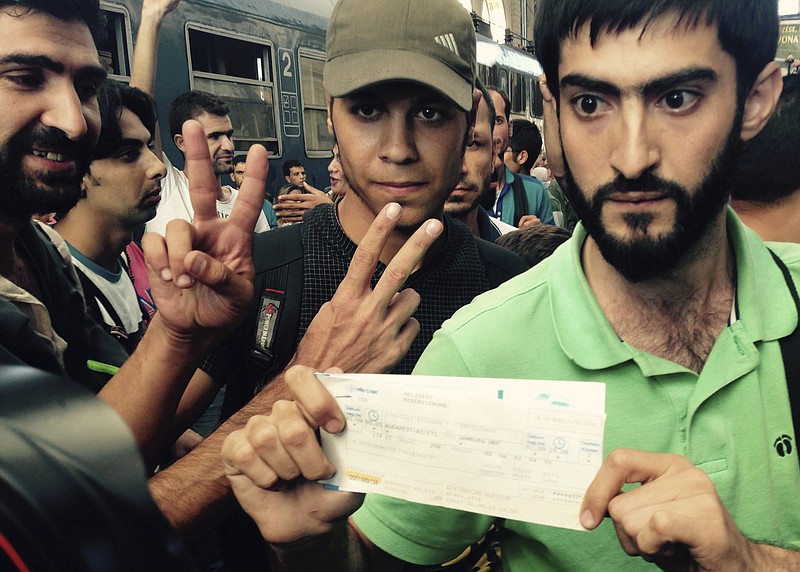 
              Syrian migrants show their train tickets to Germany and demand being let on the train but Keleti train terminal in Budapest, Hungary, was closed Tuesday morning Sept. 1, 2015 for an indefinite time. (AP Photo/Pablo Gorondi)
            