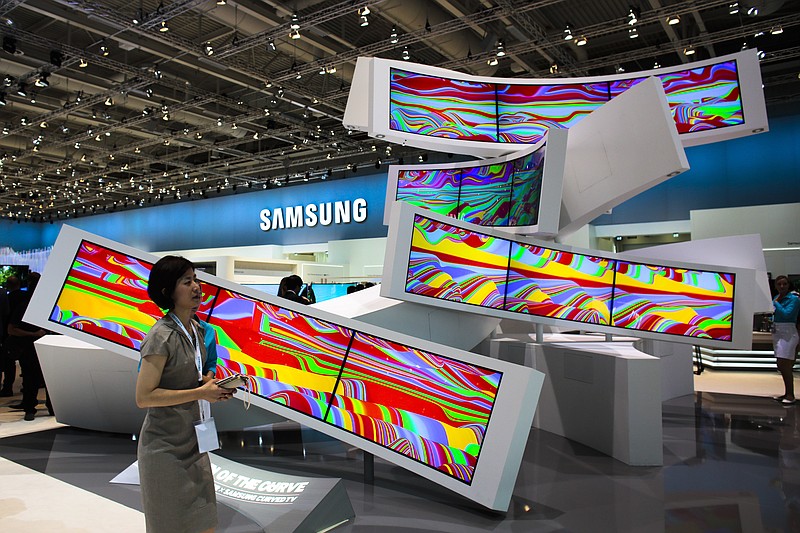 
              FILE - This is a Friday, Sept. 5, 2014 file photo of a woman as she passes an installation with curved screens, displayed by Samsung at the consumer electronic fair IFA in Berlin, Germany. Europe’s flagship gadget show, the IFA in Berlin, opens its doors to the public on Friday Sept. 4, 2015 . Almost 1,500 companies and over 250 000 people are expected to visit the event, which runs through Sept. 9. (AP Photo/Markus Schreiber)
            