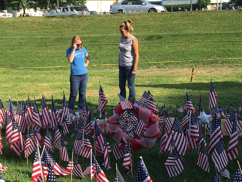 Vicki Baross, left, and Dana Anderson tend the roadside memorial for five fallen servicemen near Amnicola Highway.