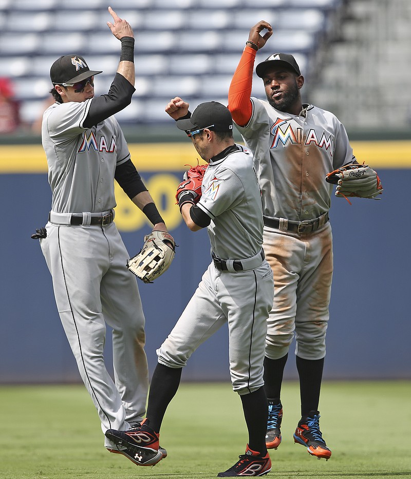 Miami Marlins outfielders Christian Yelich, left, Ichiro Suzuki, center, and Marcell Ozuna celebrate after the final out in the ninth inning of a baseball game against the Atlanta Braves Wednesday, Sept. 2, 2015, in Atlanta. Miami won 7-3.