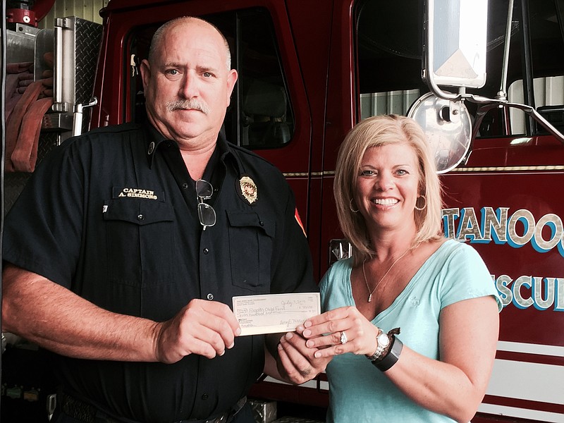 Amy Maxwell presents a donation to Captain Kelly Simmons, Chattanooga Fire Department and president, Chattanooga Forgotten Child Fund.