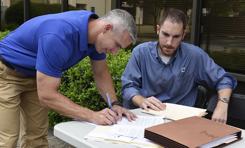 Ryan Dillard of the Dillard Partnership signs a document while Mike Tindle of TVA watches after he made the winning bid in a public auction of the former Tennessee American Water Company building Thursday, Sept. 3, 2015, in Chattanooga, Tenn. The building is located at Broad and 11th Streets between the TVA Office Complex and the Public Library.