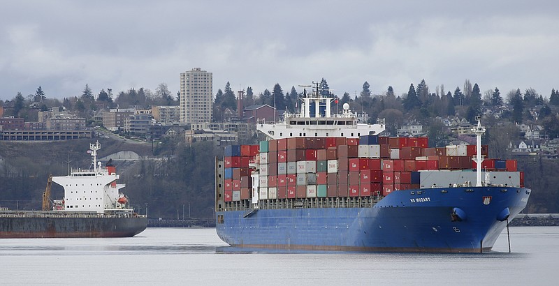 
              FILE - In this Feb. 20, 2015 file photo, the HS Mozart cargo ship, right, operated by the German shipping company Hansa Shipping, sits anchored in Commencement Bay near the Port of Tacoma, Wash. The Commerce Department reports on the U.S. trade gap for July on Thursday, Sept. 3, 2015. (AP Photo/Ted S. Warren, File)
            
