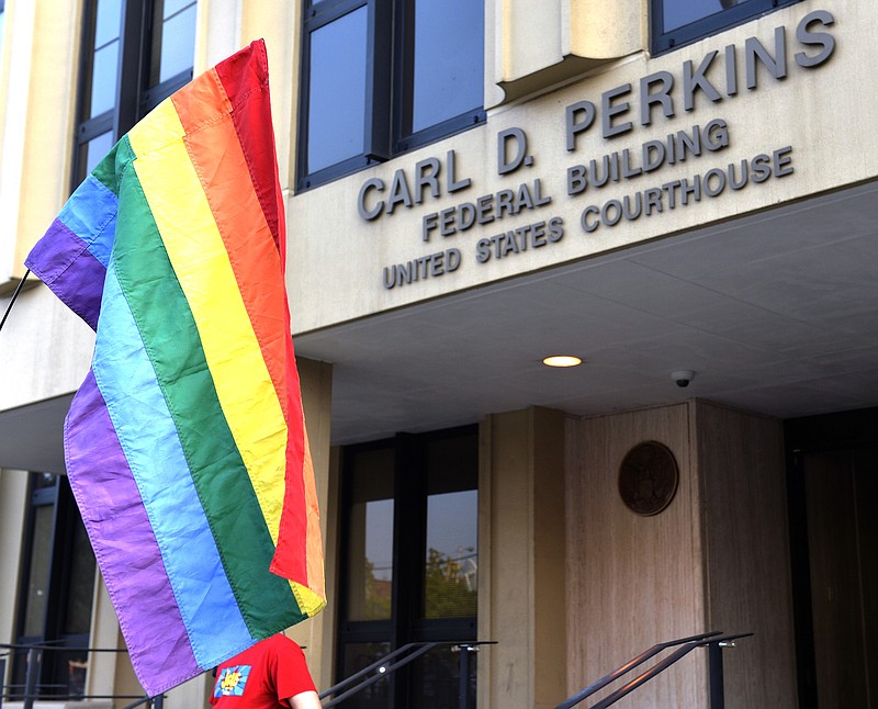 A protester waives a rainbow flag outside the Carl D. Perkins Federal Building in Ashland, Ky., Thursday, Sept. 3, 2015. 