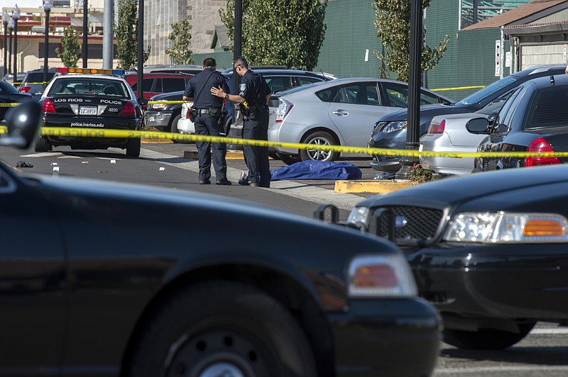 Police officers stand near the body of a victim killed in a shooting at Sacramento City College, Thursday, Sept. 3, 2015, in Sacramento, Calif. The shooting occurred in a parking lot near the baseball field on the college campus. (Renée C. Byer/The Sacramento Bee via AP) MANDATORY CREDIT