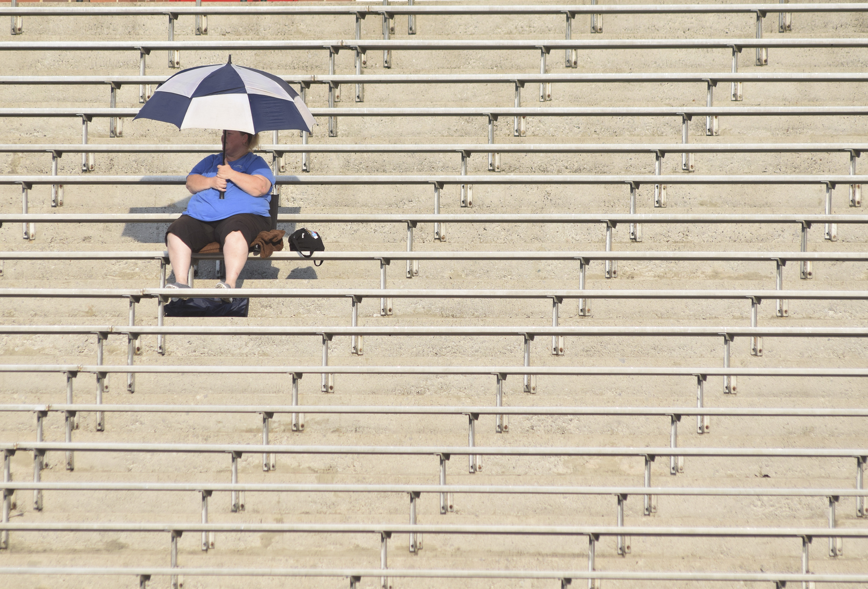 A lone East Ridge fan uses an umbrella to deflect the harsh sun before the stands fill up.  The East Ridge Pioneers hosted the Signal Mountain Eagles at Baylor School in TSSAA football action on Friday September 4, 2015.