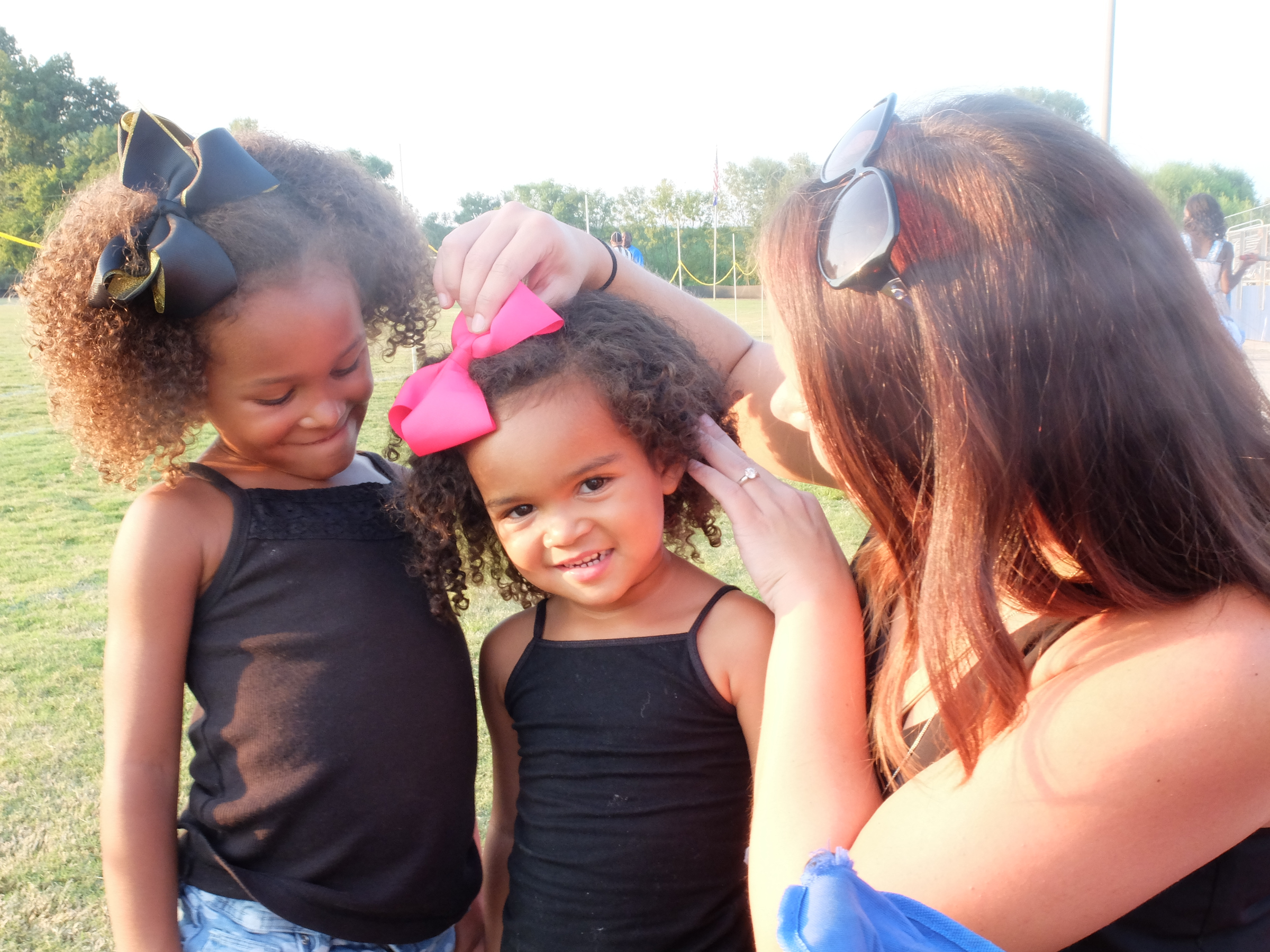 Erin Mitchell, right, adjusts the bow atop Haidyn Mitchell, center, 3, as her sister, Hailee, left, watches before their Brainerd Panthers take on Boyd-Buchanan Friday night. The Mitchell's are the family of Dr. Charles Mitchell, Brainerd High School assistant principal.