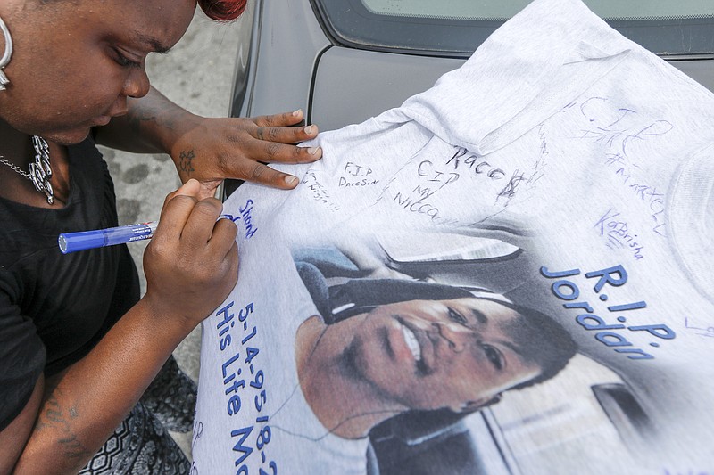 Lashonda Upshaw signs a t-shirt in memory of Jordan Clark before a donation collection at the intersection of Brainerd Road and Germantown Road to help pay for his funeral Wednesday, Sept. 2, 2015, in Chattanooga, Tenn. Clark, 20, was shot and killed on Aug. 25, and his mother, Satedra Smith, says the funeral costs are more than $5,000, so she and her family are trying to raise money.