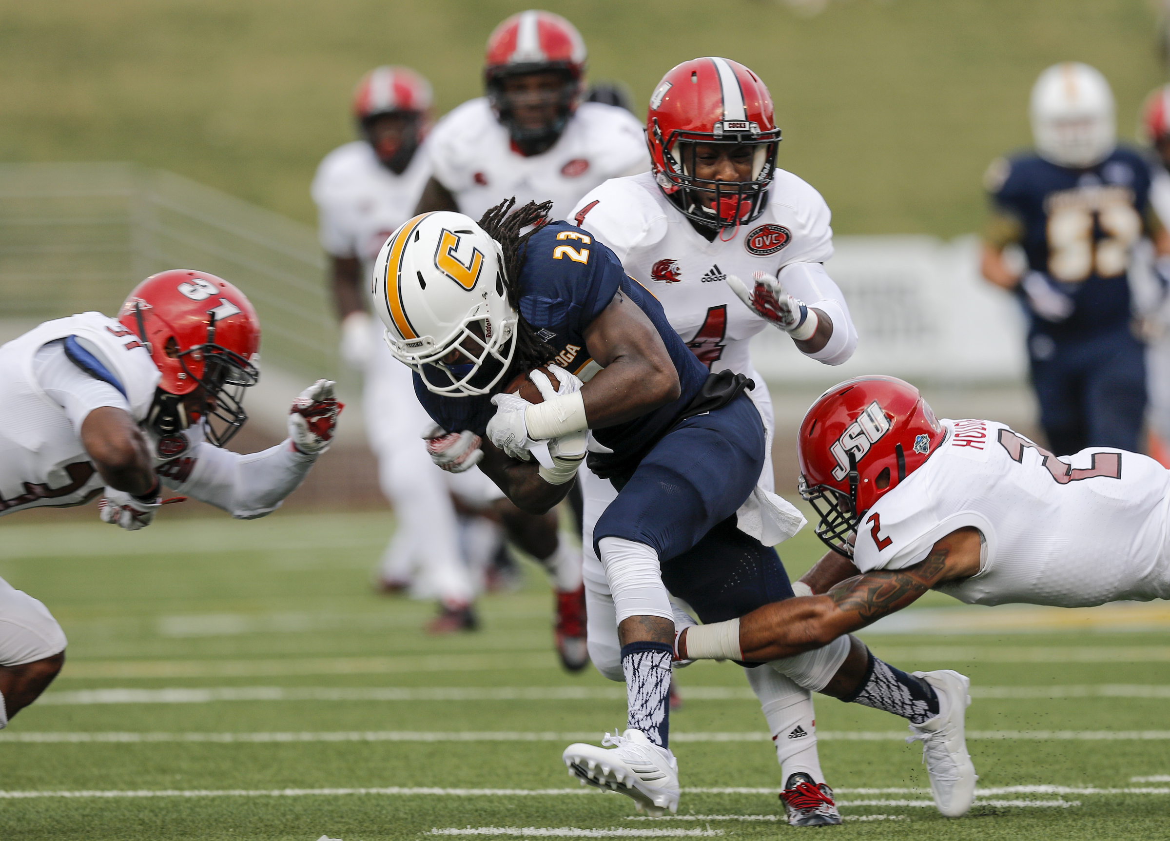 UTC running back Richardre Bagley (23) is tackled by Jacksonville State defenders Jermaine Hough (2), Folo Johnson (4), and DeBarriaus Miller (31) during the Mocs' season-opener football game against Jacksonville State at Finley Stadium on Saturday, Sept. 5, 2015, in Chattanooga, Tenn.