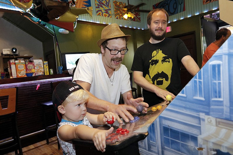 Adam Brown, right, watches TJ Greever, center, and his son Dunagan play a Ninja Turtles arcade game at the Coin-Op, a new coin operated arcade on Martin Luther King, Jr., Boulevard, on Saturday, Aug. 29, 2015, in Chattanooga, Tenn. The Coin-Op serves as an arcade, bar, and music venue.