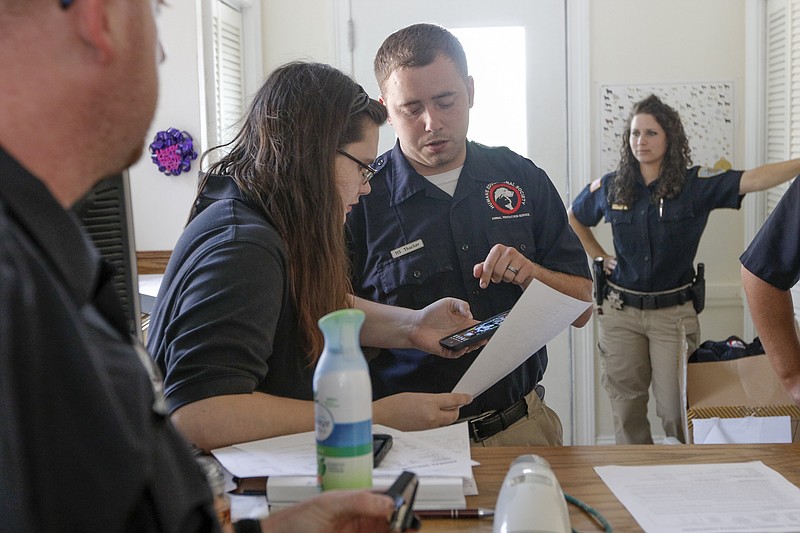 Animal patrol officers Tim Checket, left, and Krista Hooper, right, watch as fellow officer Thomas Thacker checks with dispatcher Danielle Austin at the Humane Educational Society on Friday, Sept. 4, 2015, in Chattanooga, Tenn. After an increase to the organization's budget, they are increasing the hours and availability of animal control services.