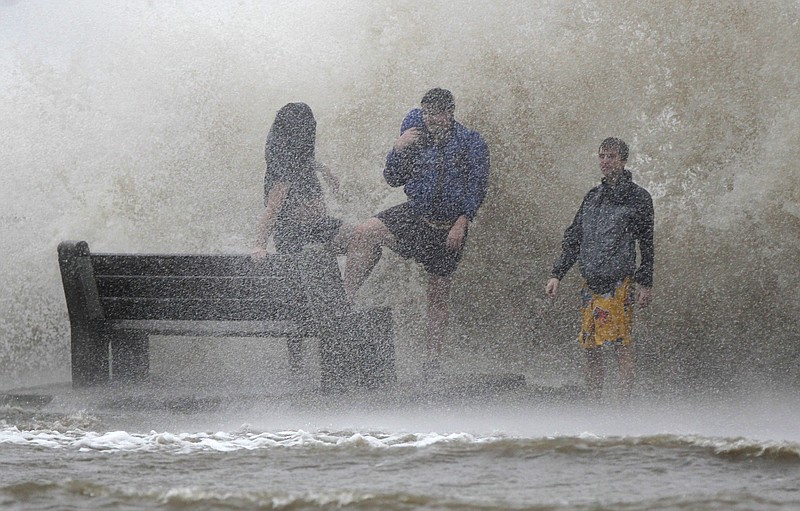 People walk in the storm surge from Hurricane Isaac, on Lakeshore Drive along Lake Pontchartrain, as the storm approaches landfall, in New Orleans, in 2012.