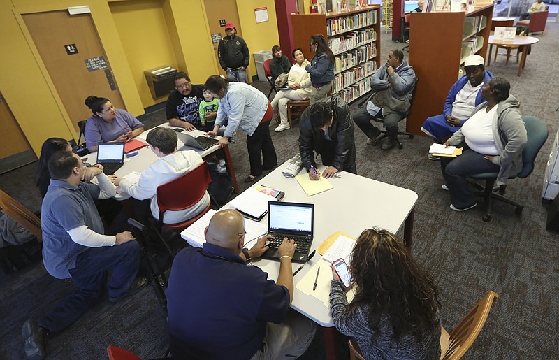 In this photo Feb. 12, 2015, file photo, Affordable Care Act navigators hold an enrollment event at the Fort Worth Public Library in Fort Worth, Texas.