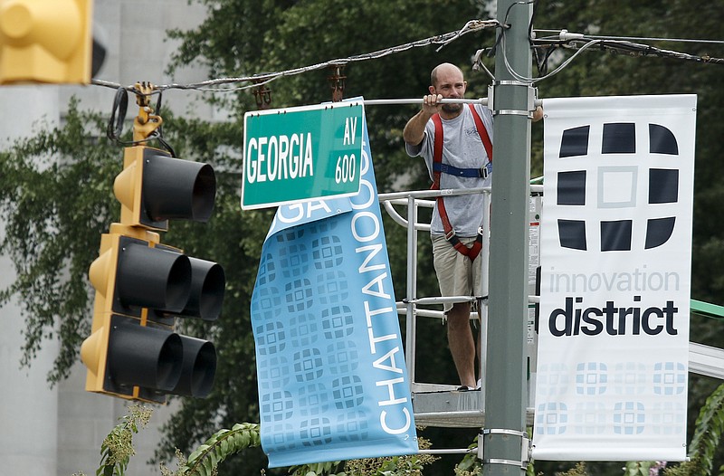 Thomas Ray with Inview Graphics hangs new light post banners, including a banner advertising the so-called "Innovation District, " at the intersection of 7th Street and Georgia Avenue on Wednesday, Sept. 9, 2015, in Chattanooga, Tenn. The graphics company is hanging 62 new banners in the area from 11th Street to 7th Street around Market and Broad Streets and Georgia Avenue.