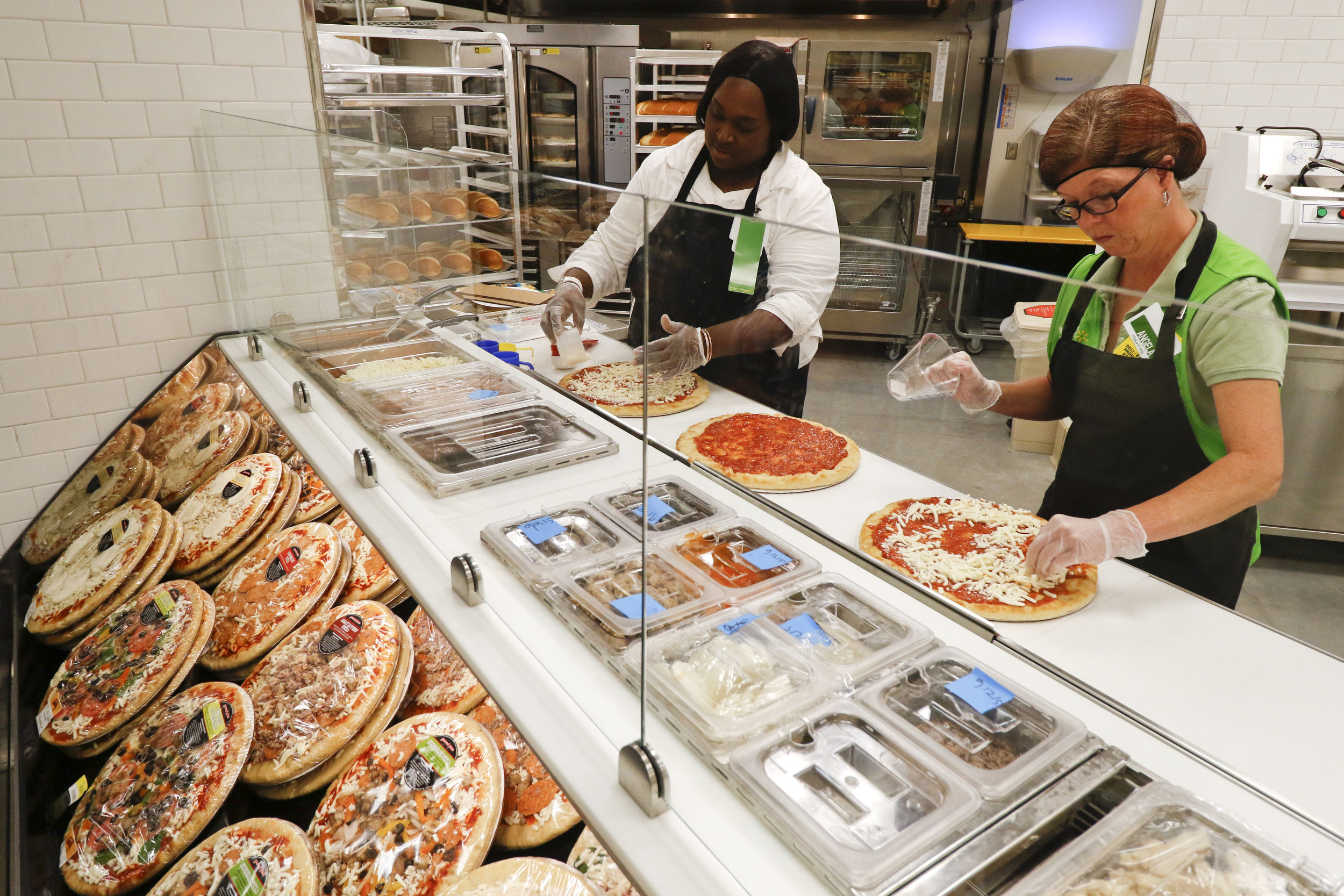 Loaned Gurley, left, and Angela Qualls make pizzas during the grand opening of the Walmart Neighborhood Market off of East Brainerd Road in Chattanooga, Tenn., on September 9, 2015.