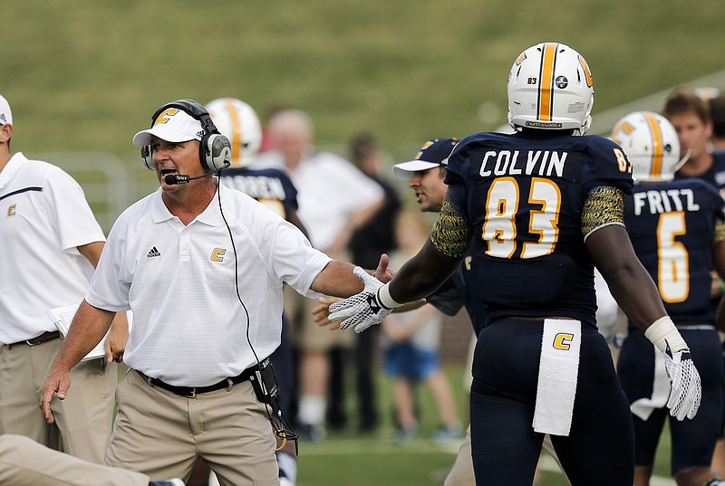 UTC head coach Russ Huesman claps the hand of UTC tight end Malcolm Colvin during the Mocs' season-opener football game against Jacksonville State at Finley Stadium on Saturday, Sept. 5, 2015, in Chattanooga, Tenn.