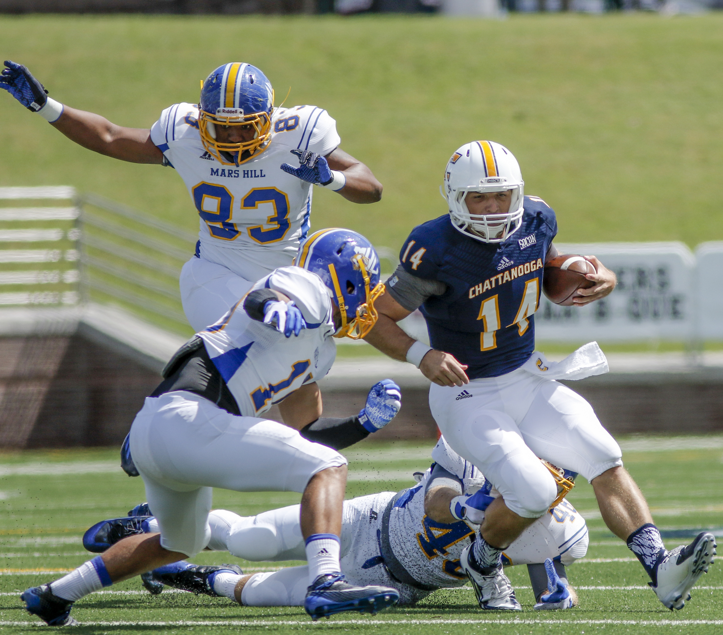 UTC quarterback Jacob Huesman (14) breaks around Mars Hill defensive end Markece Cunningham (83) and defensive back Trey Clark during the Mocs' football game against the Lions at Finley Stadium on Saturday, Sept. 12, 2015, in Chattanooga, Tenn. UTC won 44-34.