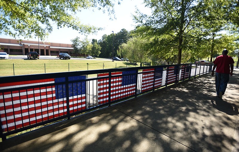 A man walks past five American flags hang on the railing of the Tennessee Riverwalk in front of the Navy & Marine Corps Reserve Center on Tuesday, September 15, 2015.