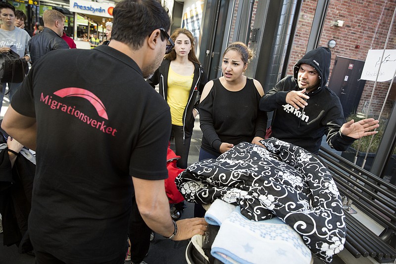 
              In this image taken Tuesday Sept. 8, 2015 a newly arrived migrant family, right, speak with an officer of the Swedish Migration Agency at the Central Station in Malmo Sweden .  The bleary-eyed migrants arriving in Malmo's glass-and-steel train station agreed on one thing: Sweden was a better place to go than Denmark, which has cut welfare benefits for refugees. (Ola Torkelsson/TT  via AP) SWEDEN OUT
            