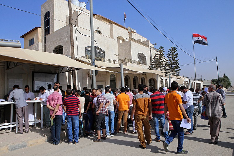 In this Sept. 15, 2015 photo, Syrian refugees gather outside their embassy waiting to apply for passports or to renew their old ones, in Amman, Jordan. Hundreds of Syrian refugees line up at their country's embassy every day for a long shot at a better future in Europe: They apply for Syrian passports that can get them into Turkey without visas, and from there plan to start dangerous journeys by sea and land to the continent. (AP Photo/Raad Adayleh)
            