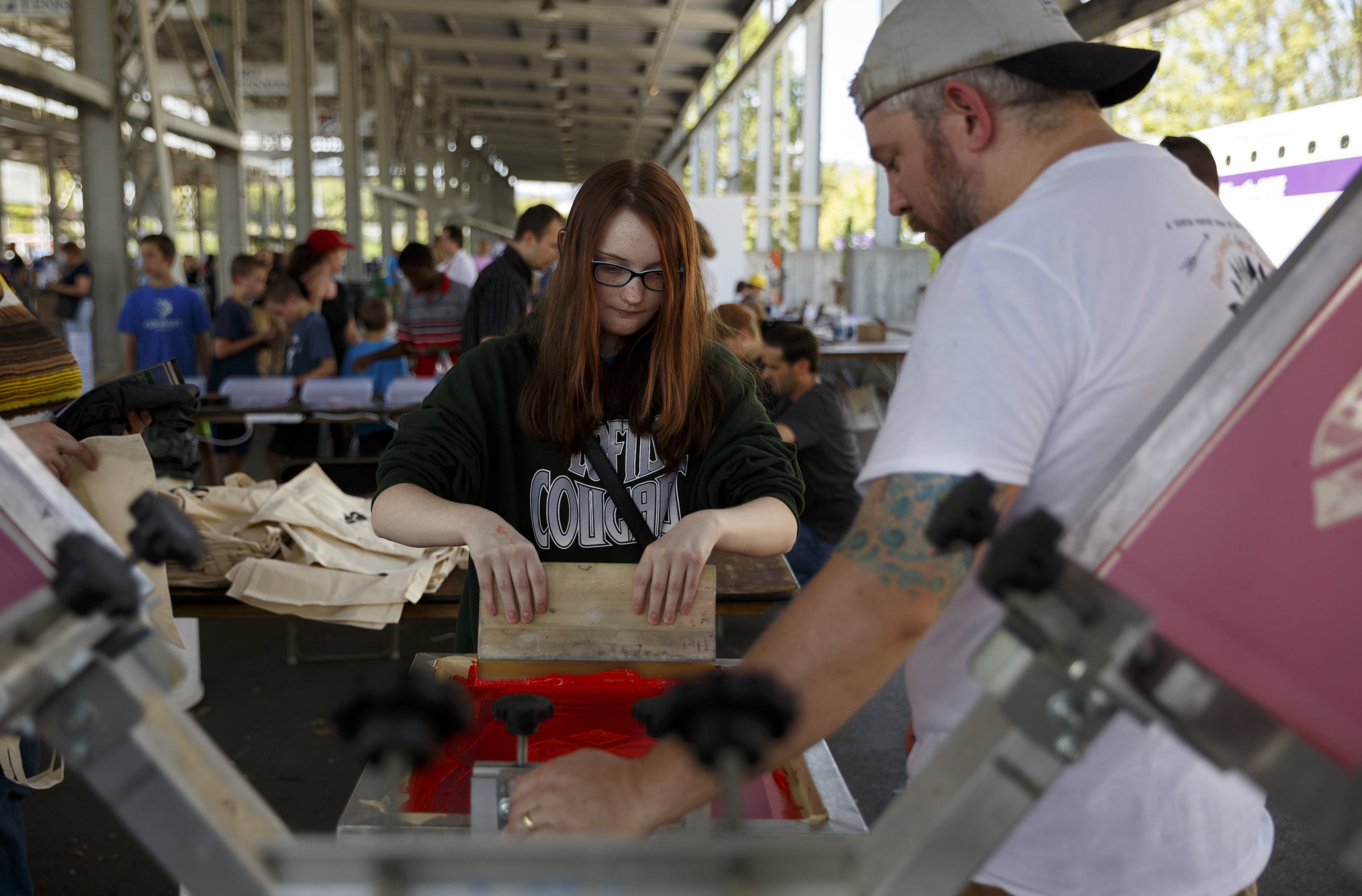 Casey Whitaker, right, helps Hope Hall put a screen printed logo onto a tote bag at the Chattanooga Mini Maker Faire at the First Tennessee Pavilion on Saturday, Sept. 19, 2015, in Chattanooga, Tenn. The faire is a celebration of creators and their creations, and it showcased makers ranging from technology enthusiasts to crafts artisans.