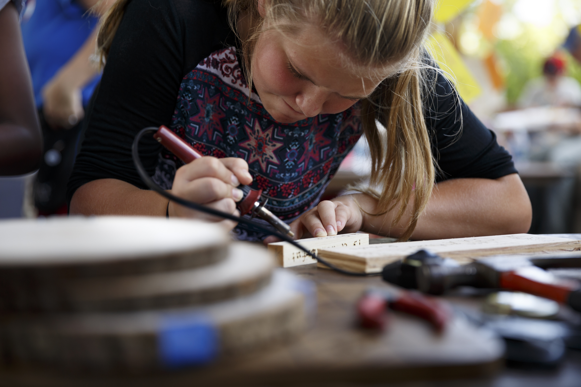 Lily Akins uses a tool to burn decorations into a block of wood, known as pyrography, at a booth during the Chattanooga Mini Maker Faire at the First Tennessee Pavilion on Saturday, Sept. 19, 2015, in Chattanooga, Tenn. The faire is a celebration of creators and their creations, and it showcased makers ranging from technology enthusiasts to crafts artisans.