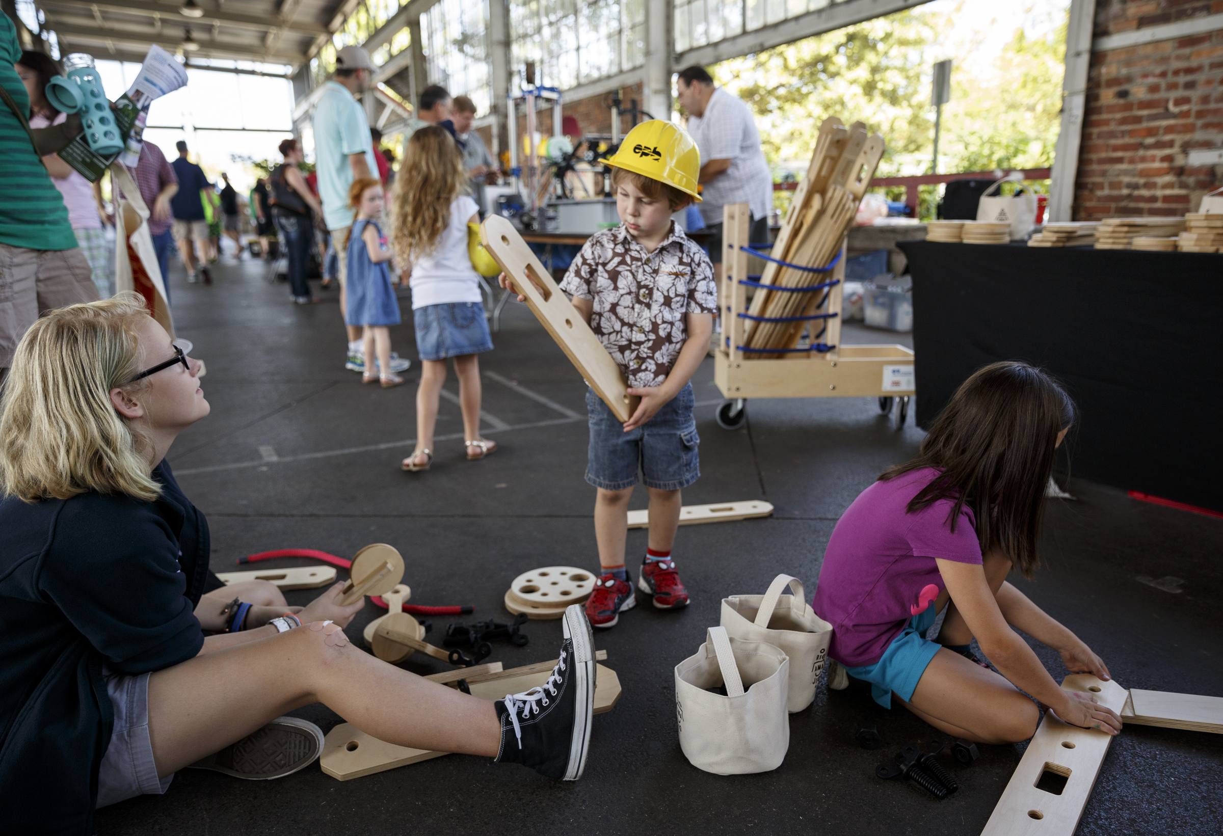 Danica Leslie, Josyah Eaton, and Arabella Eaton, from right, connect sections of wood toys at a booth during the Chattanooga Mini Maker Faire at the First Tennessee Pavilion on Saturday, Sept. 19, 2015, in Chattanooga, Tenn. The faire is a celebration of creators and their creations, and it showcased makers ranging from technology enthusiasts to crafts artisans.
