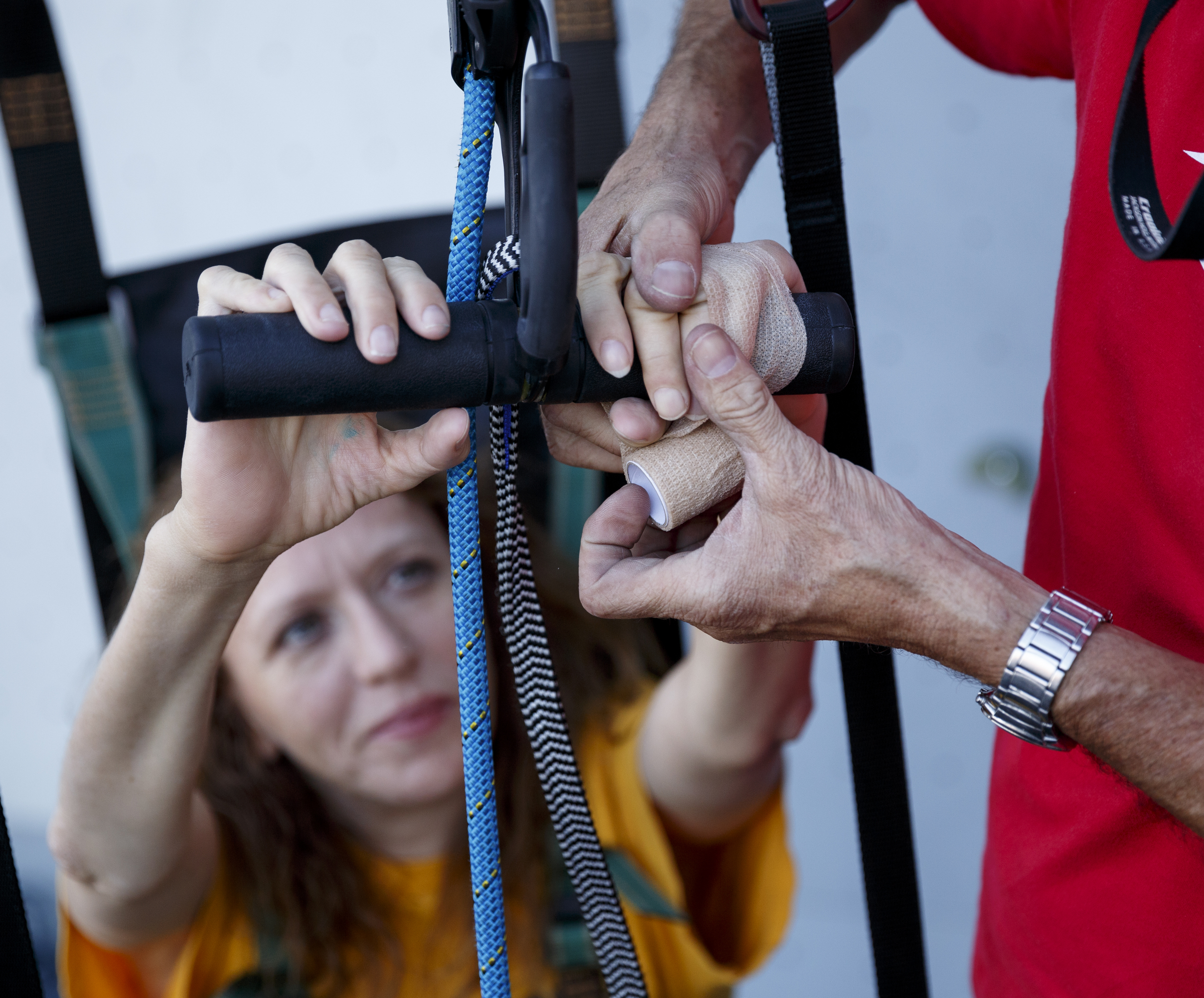 Fred Vail uses athletic tape to secure Charity Trillet's hands to an ascender device before she climbs a wall using a Wellman System harness, which allows climbers to ascend without using their legs, during an adaptive climbing program at High Point Climbing gym Thursday, Sept. 17, 2015, in Chattanooga, Tenn. Some climbers in the program have trouble gripping the ascender, says Vail, so his solution was tape. The program, which happens on the third Thursday of each month, provides resources to help disabled climbers enjoy the sport.