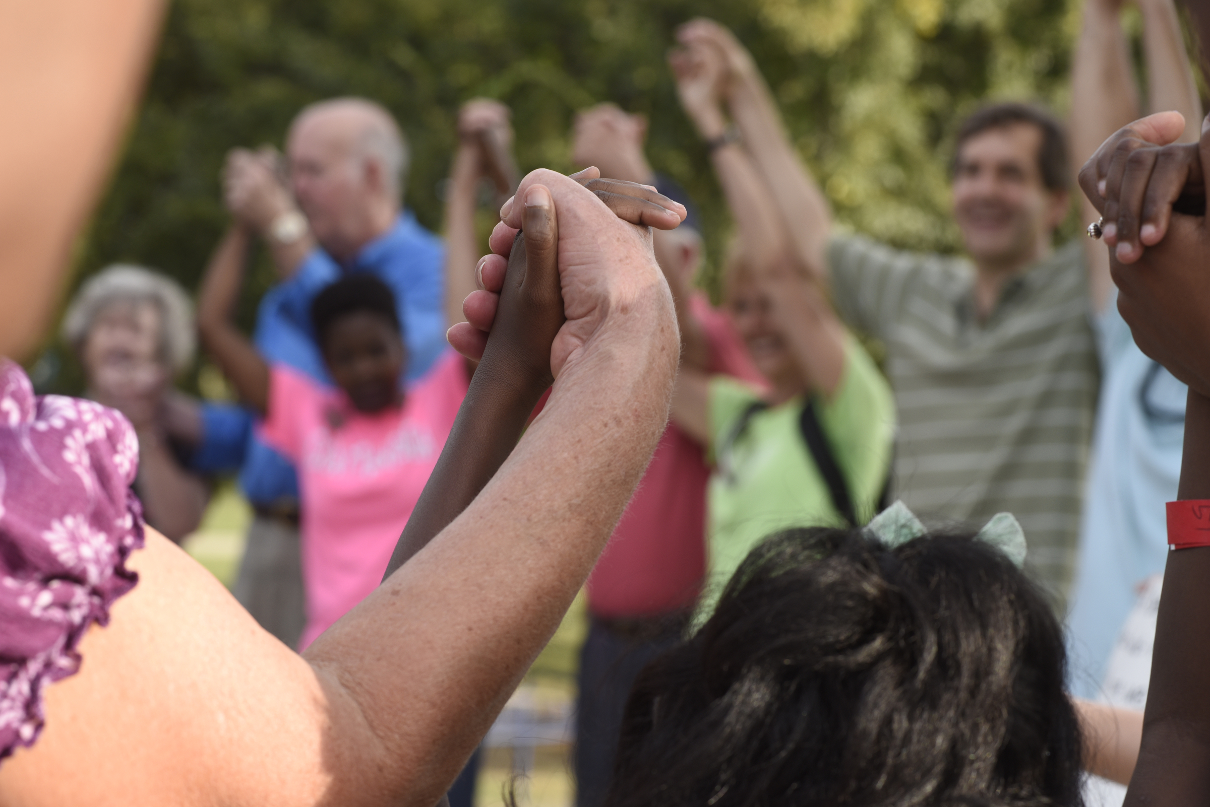 People raise their hands joined in prayer at Coolidge Park on Sunday, Sept. 20, 2015, in Chattanooga, Tenn., during an event in remembrance of families affected by violence.