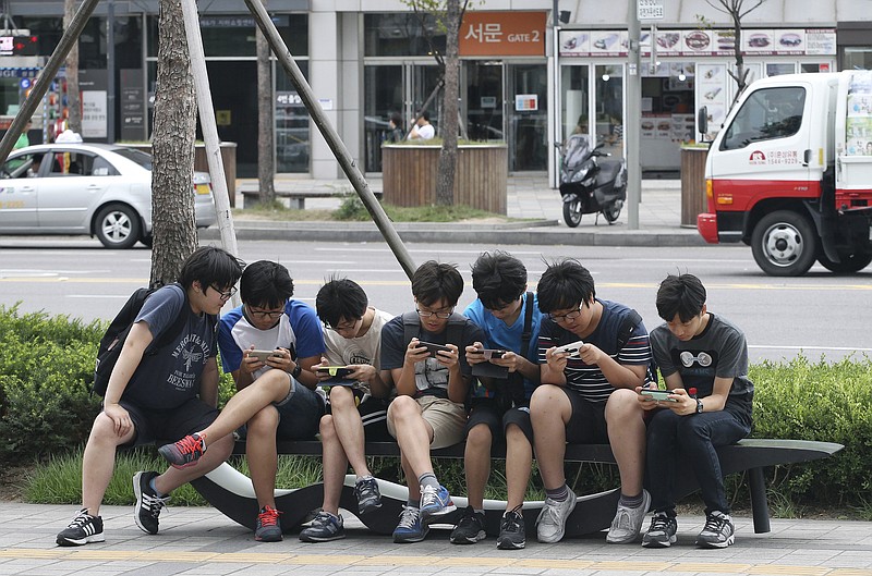 
              FILE - In this July 16, 2015, file photo, South Korean high school students play games on their smartphones on a bench on the sidewalk in Seoul, South Korea. Security researchers say they found critical weaknesses in a South Korean government-mandated child surveillance app, vulnerabilities that could have allowed hackers to easily violate the private lives of the country’s youngest citizens. (AP Photo/Ahn Young-joon, File)
            