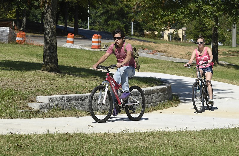 Mickey Cruz, left, and Jennifer Rush ride bicycles on a completed section of a new sidewalk for bicycles and pedestrians under construction along Highway 58 on Tuesday, Sept. 15, 2015, in Chattanooga, Tenn. 