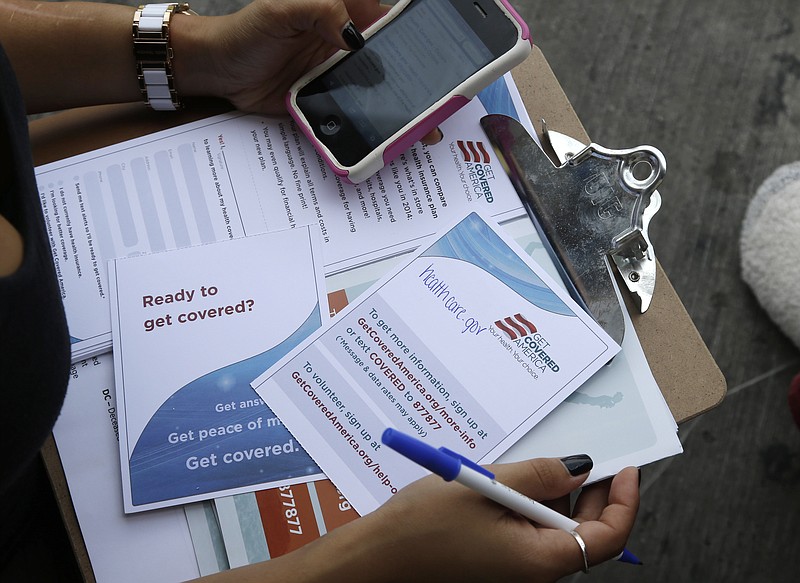 In a 2013 photo, a field organizer with Enroll America holds a clipboard with Affordable Health Care Act pamphlets as she attempts to enroll people in the program at a bus stop in Miami.