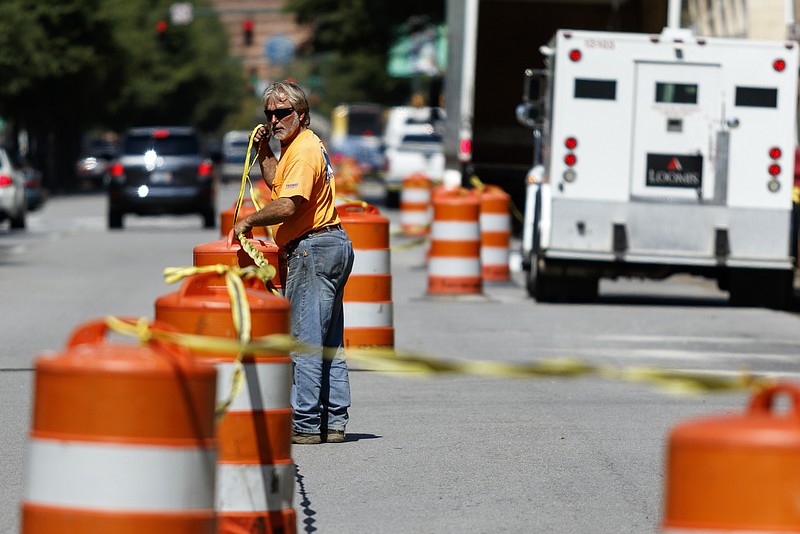 Daniel Smith arranges orange traffic cones to block off on-street parking on the northbound side of Broad Street in preparation for the installation of a protected bike lane Wednesday in Chattanooga.