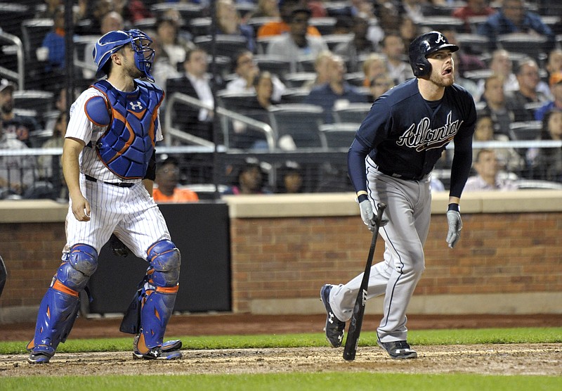 Atlanta Braves pinch-hitter Freddie Freeman, right, watches a two-run double in front of New York Mets catcher Travid d'Arnaud during the seventh inning of a baseball game Wednesday, Sept. 23, 2015, in New York.