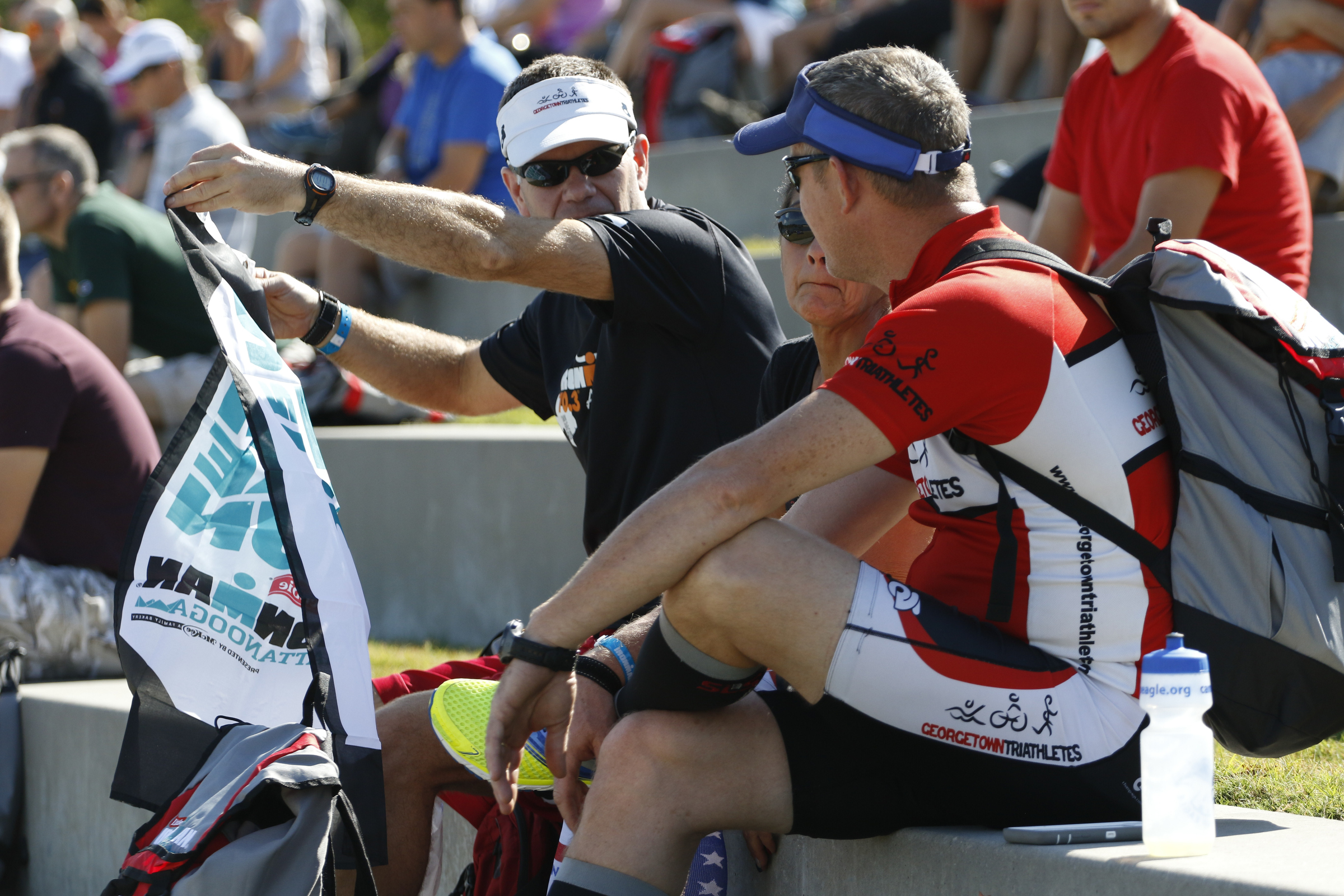 Chad Moore holds up a IM flag to show his fellow Georgetown, Texas, friends Christine Knight and Chad Moore as they listen to the first athlete briefing meeting of the day in preparation for the second annual Ironman Chattanooga triathlon which will take place Sunday, September 27, 2015.
