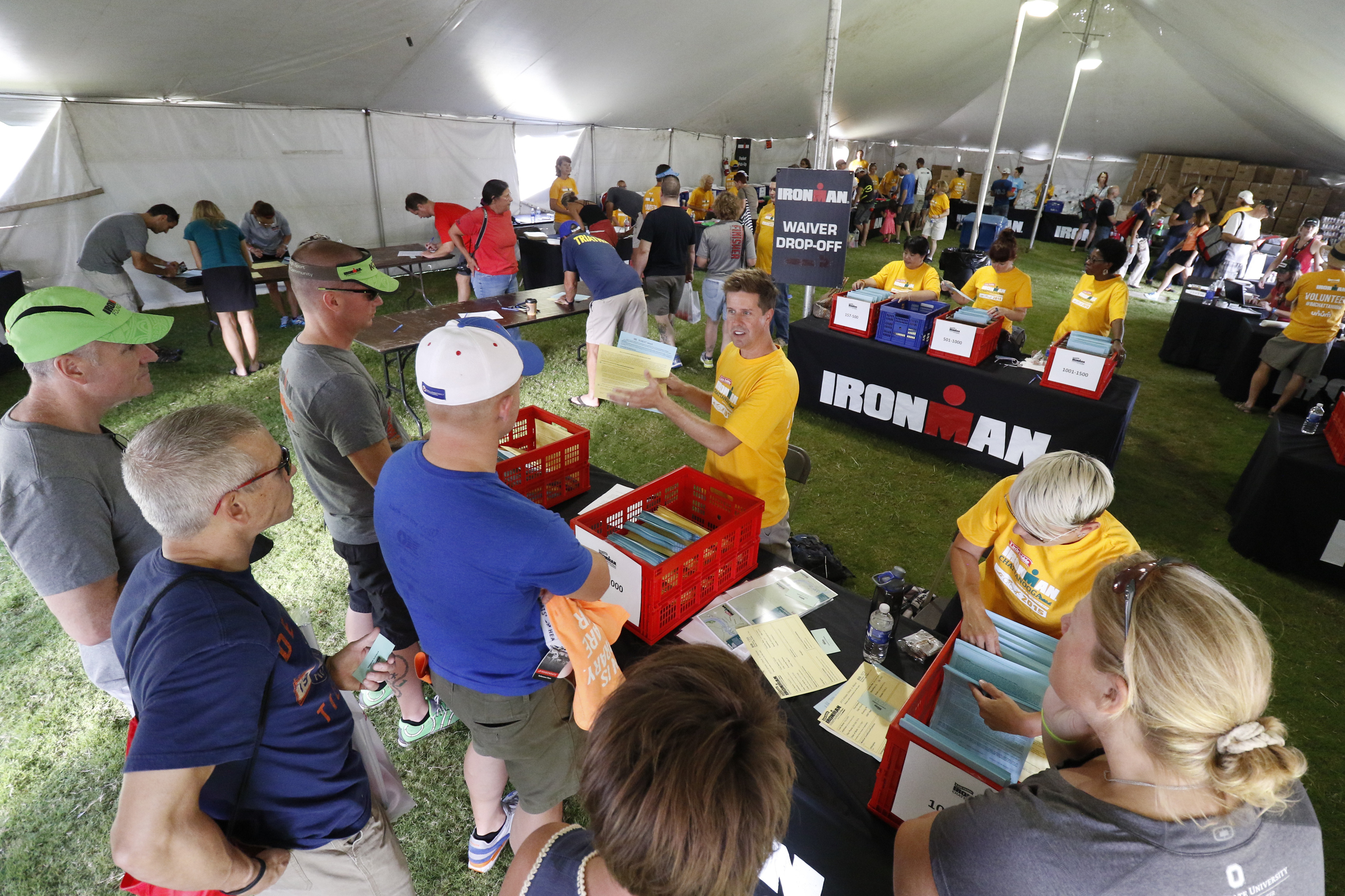 Registration volunteer Greg Higgins, center yellow, directs athletes as they pick up their bags in preparation for the second annual Ironman Chattanooga triathlon which will take place Sunday, September 27, 2015.