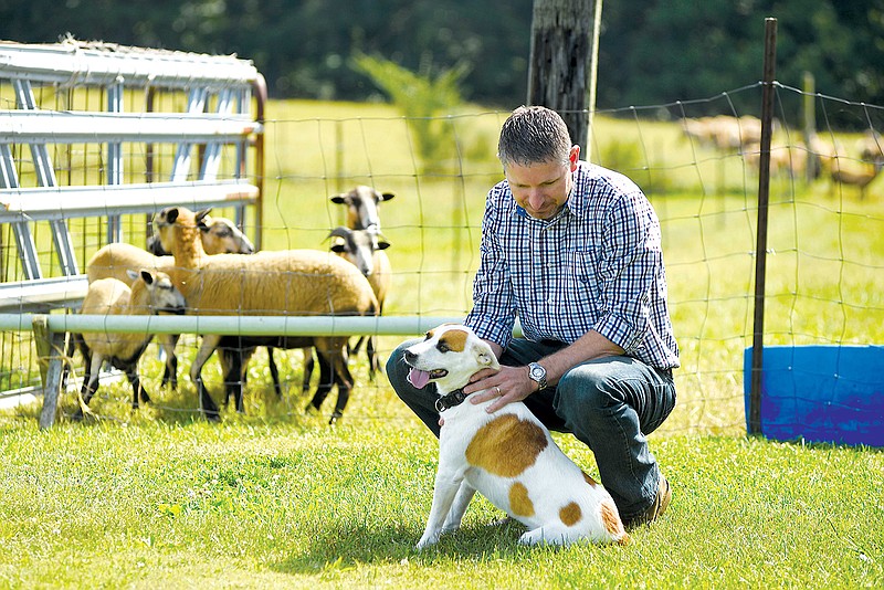 Gary Roberts takes a break from his job working for Unum on his farm near Dayton, Tennessee, to pet his dog Lucy and feed his sheep.
