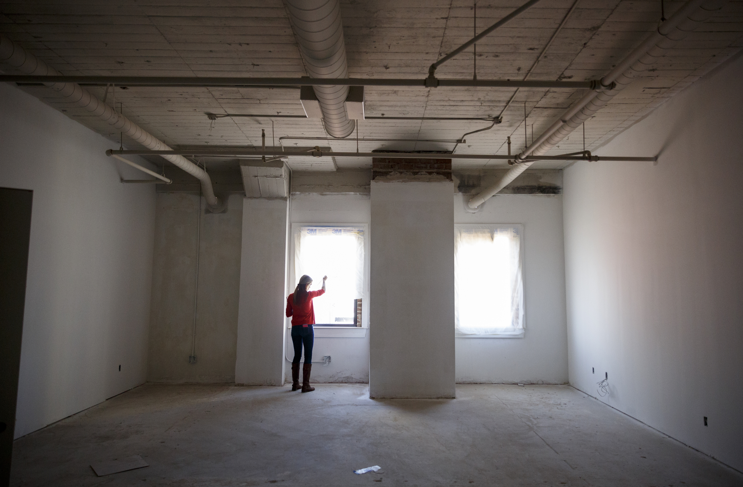 Gabby Palmer pulls a tarp away from the window of a 3-bedroom loft under construction at the Clemons building Wednesday, Sept. 23, 2015, in Chattanooga, Tenn. The building, which dates back to the early 1920s, is being restored to offer luxury downtown loft apartments by owner and developer Vic Desai.