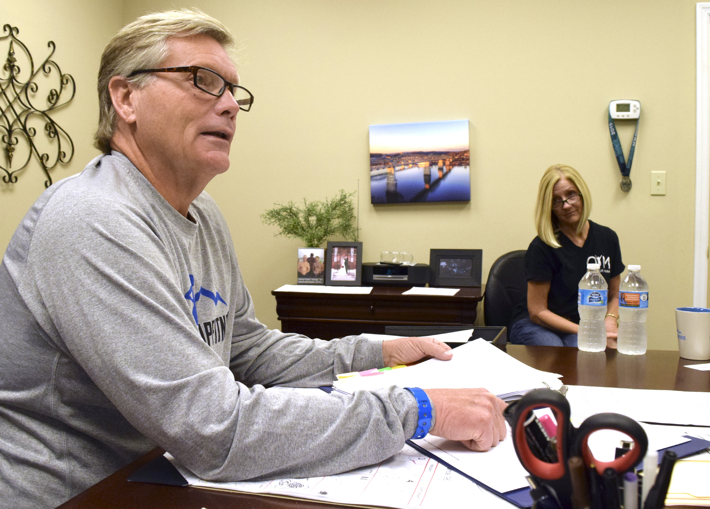 Steve Bean looks at the training manual that his son, Cameron Bean, created for him to prepare for the Ironman competition on Sunday. Steve's wife, Lisa, looks on in the background. Cameron Bean died Monday after being hit by a car while running.