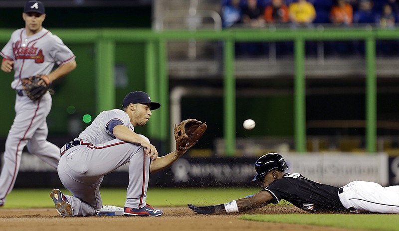 Miami Marlins' Dee Gordon, right, steals second base as Atlanta Braves shortstop Andrelton Simmons, center, awaits the late throw as Braves' Jace Peterson, left, backs up the play in their game, Sunday, Sept. 27, 2015, in Miami. 