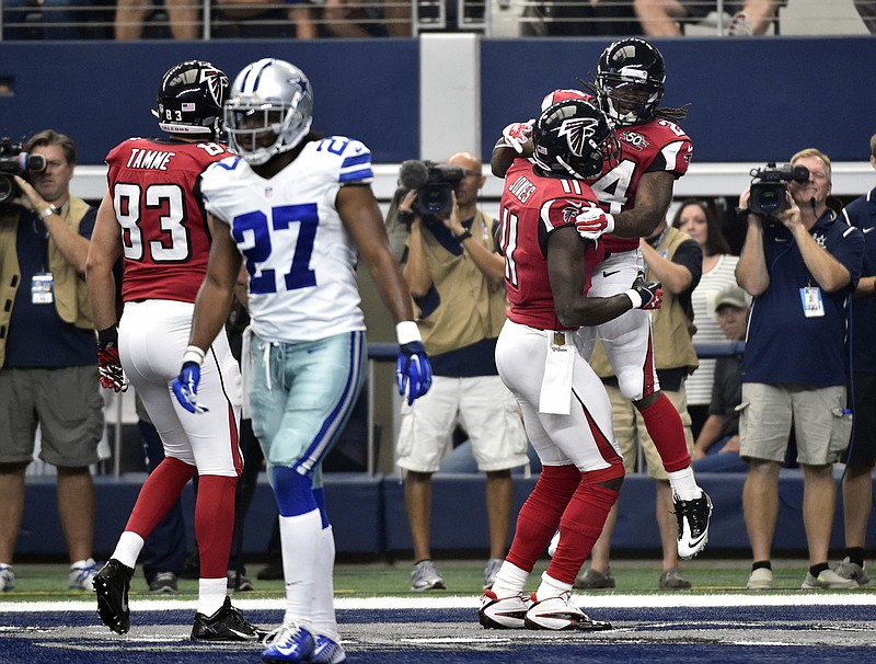 Dallas Cowboys free safety J.J. Wilcox (27) walks away as Atlanta Falcons' Jacob Tamme (83) and Julio Jones (11) celebrate with Devonta Freeman (24) after Freeman scored a touchdown in the first half of an NFL football game on Sunday, Sept. 27, 2015, in Arlington, Texas. 