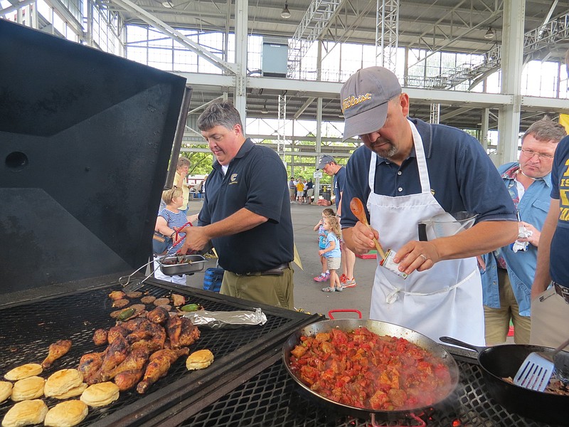 Paul Schoner, left, and Rob Varner man the 6-foot grill they tow to First Tennessee Pavilion on game days. Varner is making chicken and sausage paella. Varner and Chip Hassler founded the Chamberlain Tailgaters in 1989 when they would tailgate at the Mocs' old Chamberlain Field.