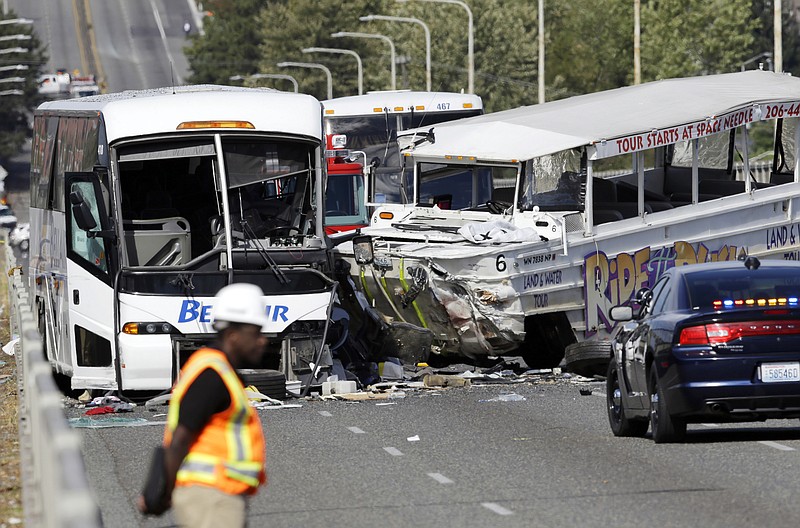 
              An emergency official stands near a charter bus, left, and a "Ride the Ducks" amphibious tour bus following a fatal crash that killed five people Thursday, Sept. 24, 2015, in Seattle. The duck boat did not have an axle repair that was recommended for at least some of the amphibious tour vehicles in 2013, federal investigators said.(AP Photo/Ted S. Warren)
            