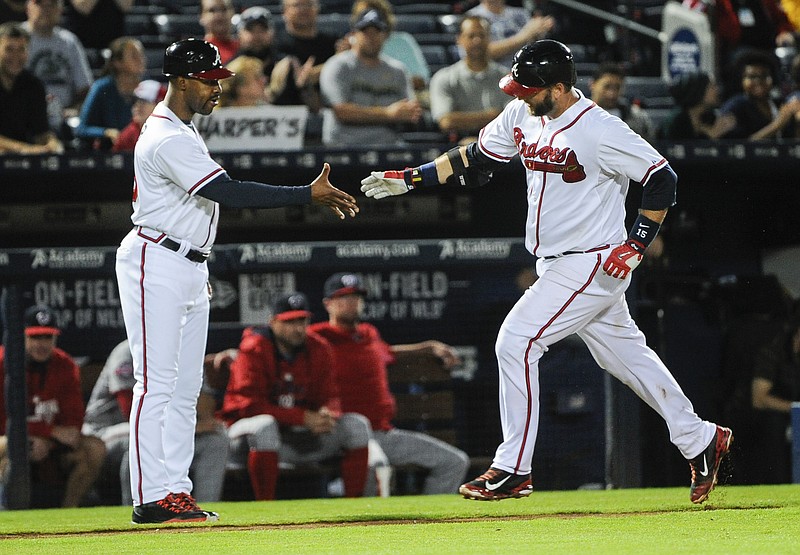 Atlanta Braves' A.J. Pierzynski rounds their base to congratulations by coach Bo Porter, left, during a home run against the Washington Nationals in the seventh inning of a baseball game, Tuesday, Sept. 29, 2015, in Atlanta.