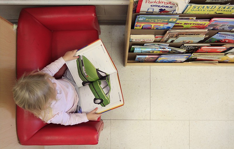 A youngster reads a book during her 2011 pre-K class.