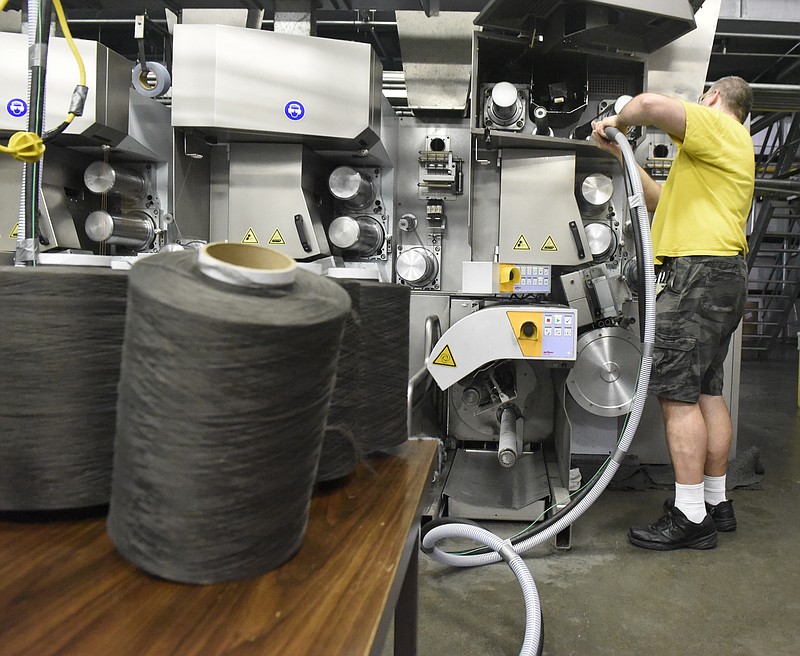 Christopher Sand uses a vacuum on an extruder to gather loose carpet fibers that are saved for recycling at the J + J Flooring Group facility Monday, Sept. 28, 2015, in Dalton, Ga. 